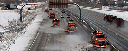 Multiple snow plows on the freeway